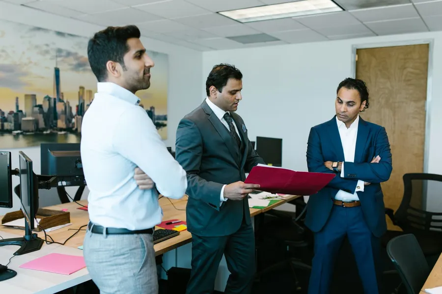 Three senior professionals in business attire discussing a document together